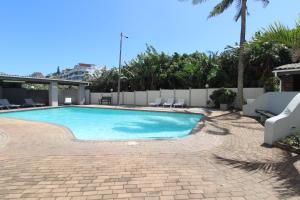 a swimming pool with chairs and a palm tree at Santana 905 in Margate