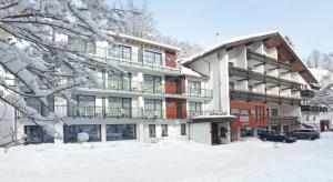 ein Gebäude mit Schnee auf dem Boden davor in der Unterkunft Flair Hotel Sonnenhof in Baiersbronn