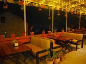 a patio with two tables and chairs and lights at The Nest Guest House in Changunarayan
