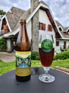 カンポス・ド・ジョルドンにあるCasa Três Rios - Campos do Jordãoのグラスの横のテーブルに座るビール1本