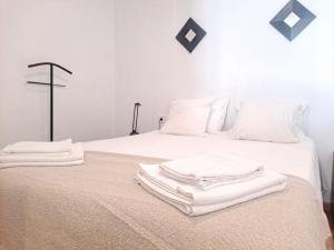 two white towels are stacked on top of a bed at Fantástico loft cerca centro by Lofties in Terrassa