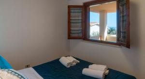 a bedroom with a mirror and a bed with towels at Casa dei Lentischi in Cala Gonone