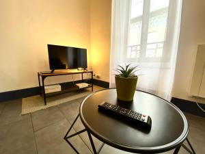 una sala de estar con una mesa con mando a distancia. en Spacieux, Climatisé, Quartier Calme, Proche Château, Le Cocon De Joy en Carcassonne
