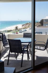 Cottesloe Beach View Apartments #11 في بيرث: طاولة وكراسي على شرفة مطلة على الشاطئ