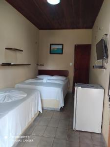 a bedroom with two beds and a tv at Pousada Via Lactea in Canoa Quebrada