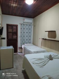a room with two beds in a room with a door at Pousada Via Lactea in Canoa Quebrada