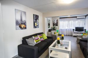 a living room with a black couch and a tv at Ayia Napa Holiday Apartment So7 in Ayia Napa