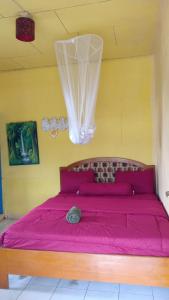 a bed with a pink comforter in a room at Hobbit Hill in Ruteng