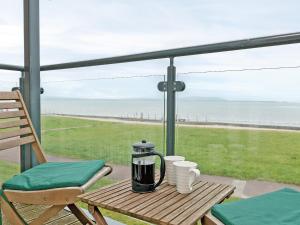 einen Tisch mit einer Kaffeemaschine und einem Stuhl auf dem Balkon in der Unterkunft Beachlands in Llanelli