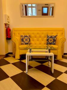 um sofá amarelo numa sala de estar com uma mesa de centro em Topolove Rooms & Apartments em Cracóvia