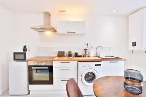 a kitchen with a table and a washer and dryer at Little Factory - T2 avec parking in Vierzon
