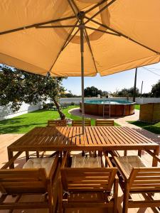 einen Holztisch und Stühle unter einem Sonnenschirm in der Unterkunft Sanzi Country House in Tavira