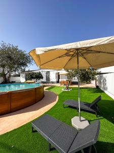 a patio with an umbrella and two chairs and a pool at Sanzi Country House in Tavira