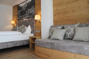 a bedroom with two beds and a couch at B&B Relais Dolomiti in Bedollo