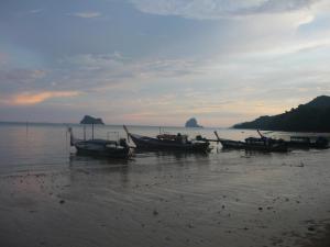 a group of boats sitting on the shore of the water at Pasai Beach Lodge in Ko Yao Noi