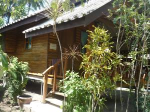 Pasai Beach Lodge في كو ياو نوي: منزل خشبي مع شرفة وبعض النباتات