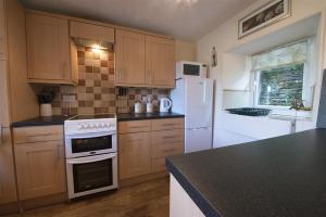 a kitchen with white appliances and a black counter top at Bank Top Cottage Coniston in Coniston