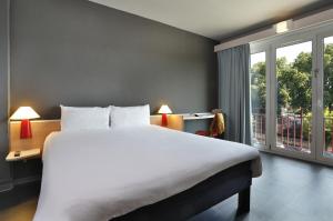 a bedroom with a large bed and a large window at Ibis Brive Centre in Brive-la-Gaillarde