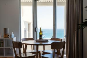 Cottesloe Beach View Apartments #11 في بيرث: غرفة طعام مع طاولة مع زجاجة من النبيذ