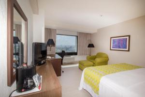 プエブラにあるHoliday Inn Puebla La Noria, an IHG Hotelのベッドとテレビが備わるホテルルームです。