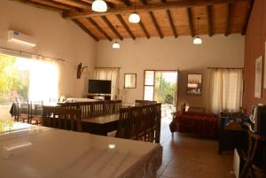 un salon avec des tables, des chaises et une télévision dans l'établissement Cabañas Bella Alba, à San Rafael