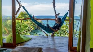 Una donna è seduta su un'amaca in veranda di Araya Dive Resort Togean a Bomba