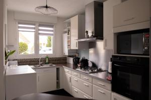 a kitchen with white cabinets and a black microwave at Maison - Le Terra Verde - Terrasse in Haguenau