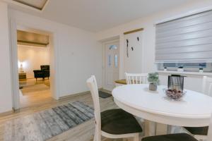 a dining room and living room with a white table and chairs at Backa idila in Bački Gračac