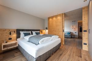 a bedroom with a large white bed and wooden walls at Small Luxury Apartments Lausa in Valdaora