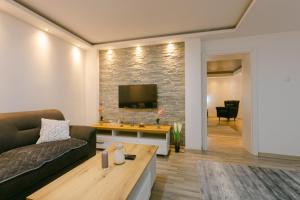 - un salon avec un canapé et une télévision sur un mur en briques dans l'établissement Backa idila, à Bački Gračac