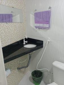 uma casa de banho com um lavatório, um WC e toalhas roxas em Pousada La Duna Lençóis Maranhenses em Barreirinhas