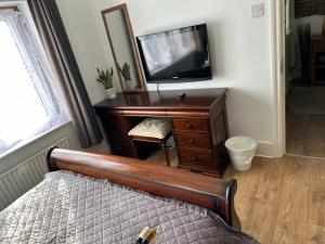 a bedroom with a bed and a dresser with a television at Amazing Quiet Garden House near London Luton Airport in Luton