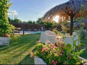 un jardín con una silla y una sombrilla y algunas flores en Cabañas Bella Alba en San Rafael