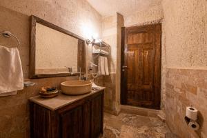 a bathroom with a sink and a wooden door at Hidden Cave Hotel in Göreme