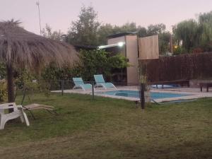 einen Pool mit blauen Stühlen neben einem Haus in der Unterkunft Cabañas Bella Alba in San Rafael