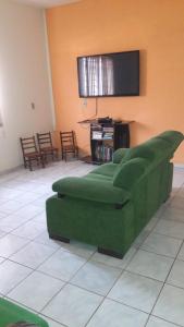 Guest Hostel 2 Marli's في بونيتو: غرفة معيشة مع أريكة خضراء وتلفزيون بشاشة مسطحة