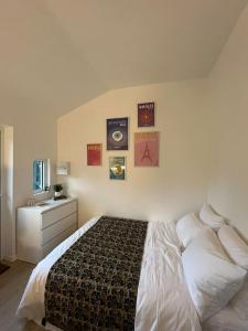 a bedroom with a bed and a dresser and pictures on the wall at Brand new Tiny House w garden in Saint-Cloud