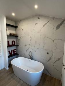 a white tub in a bathroom with a marble wall at Brand new Tiny House w garden in Saint-Cloud