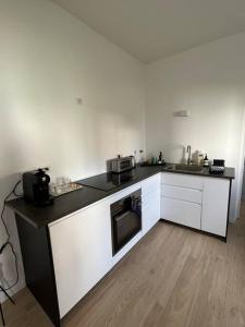 a kitchen with white cabinets and a black counter top at Brand new Tiny House w garden in Saint-Cloud