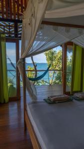 Araya Dive Resort Togean في Bomba: غرفة نوم مع سرير وإطلالة على المحيط