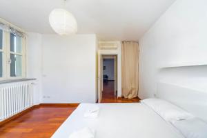 a white bedroom with a bed and a window at Cozy Flat 500m from Affori FN! in Milan