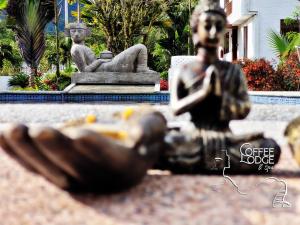 a statue of a woman reading a book next to a fountain at Coffee Lodge Cristal Glamping & Spa in Mindo