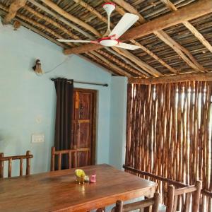 ein Esszimmer mit einem Holztisch und einem Deckenventilator in der Unterkunft Sadhna Sadan stay mountain and river view Panna tiger reserve in Rājgarh