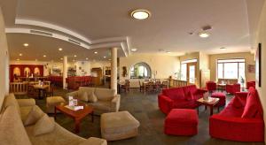 a lobby with red chairs and tables and a restaurant at Erlebnishotel Fendels in Fendels