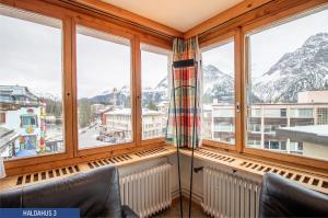 a room with windows with mountains in the background at Haus Haldahus by Arosa Holiday in Arosa