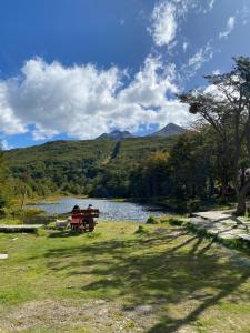 two people sitting on a bench next to a lake at del ANDINO.USH in Ushuaia