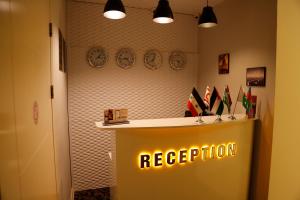 a reception desk with a neon sign on a wall at Bristol Hotel in Baku