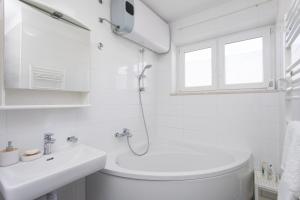 La salle de bains blanche est pourvue d'une douche et d'un lavabo. dans l'établissement BEUS DOWNTOWN, à Split