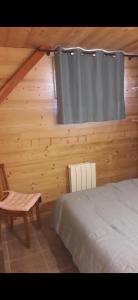 a bedroom with a bed and a window and a chair at Le Chalet de Lili in Névache