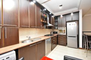 a kitchen with wooden cabinets and a stainless steel refrigerator at Prime Apartment 2 Bedroom In The Center Of Yerevan,Near Republic Square in Yerevan
